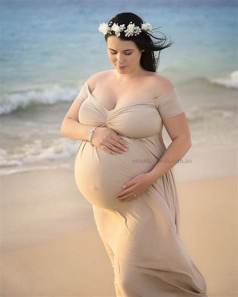 A Pregnant Woman Standing On The Beach Wearing A Flower Crown