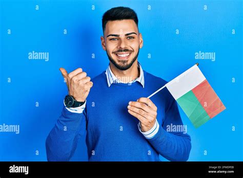 Joven Hispano Con Barba Sosteniendo La Bandera De Madagascar Apuntando