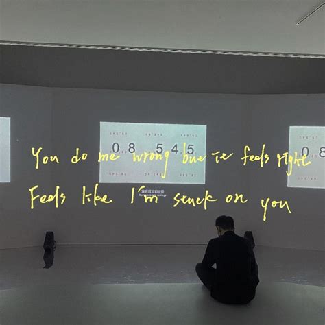 a person sitting on the floor in front of two large screens with words ...