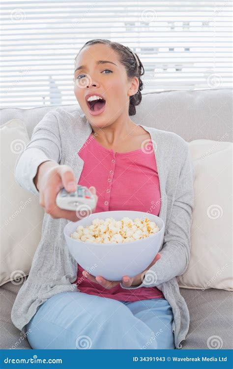 Astonished Attractive Woman Eating Popcorn While Watching Tv Stock