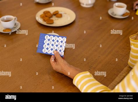 Cropped Hand Of Biracial Senior Woman Holding Bingo Card At Dining