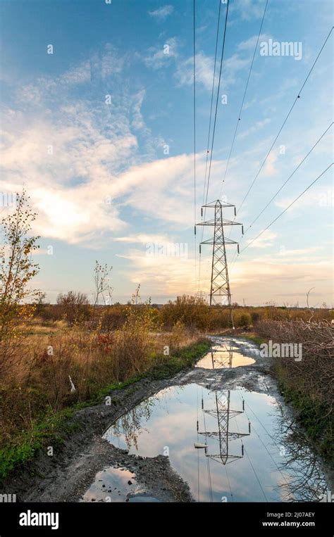 Electricity Pylon In Field With Reflection In Water Stock Photo Alamy