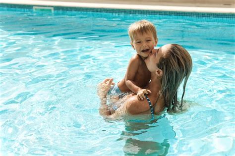 Madre y su pequeño y lindo hijo nadando en la piscina al aire libre