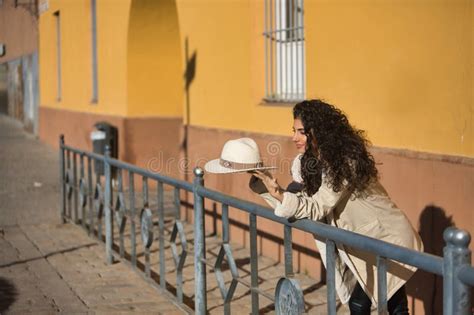 Young Pretty Brunette Woman With Curly Hair And Beige Coat And Hat