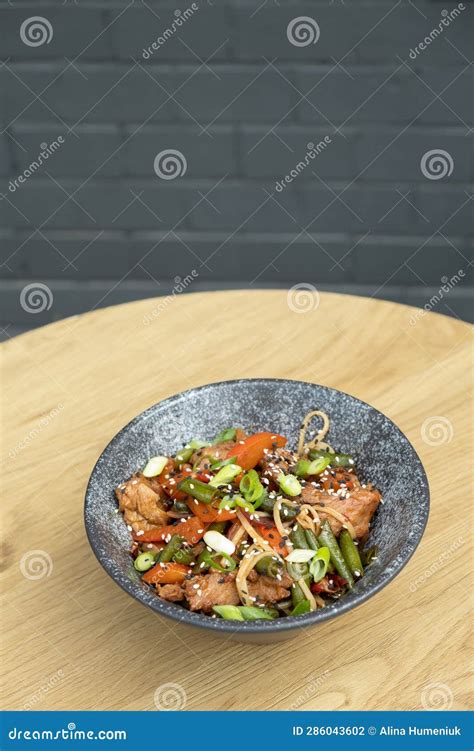 A Bowl Of Udon Noodles Veal And Fried Vegetables Angle View On Wooden