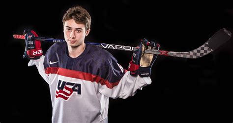 Download Portrait Of Quinn Hughes Holding Hockey Stick On Shoulders