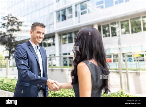 Man And Woman Dressed In Office Wear Shake Hands Outdoors In Front Of