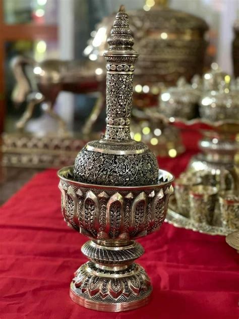 An Ornate Silver Vase Sitting On Top Of A Red Tablecloth Covered Table