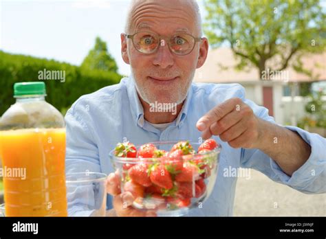 Smiling Mature Man Eating Strawberry Outside Stock Photo Alamy
