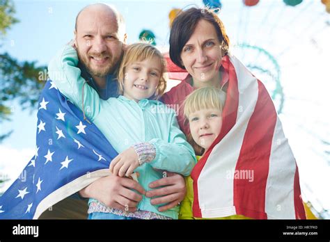 Retrato de familia patriótico con bandera americana mirando a la cámara