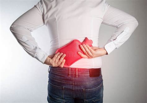 A Man Holds A Medical Heating Pad With Hot Water In The Lumbar Spine Relaxation Of The Back
