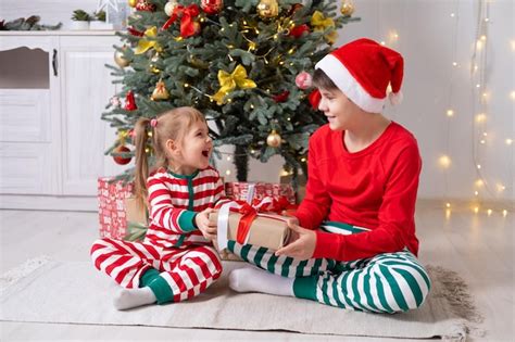 Dos niños niño y niña en pijama de navidad con cajas de regalo sentados