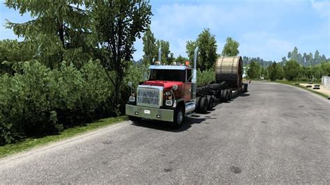 A Large Truck Driving Down A Road Next To Trees