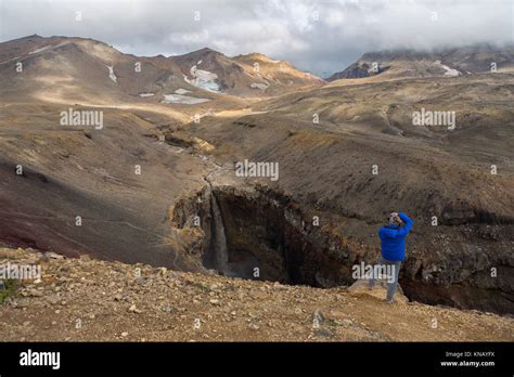 Tourist Is Taking Pictures Of A Waterfall In A Dangerous Canyon Near