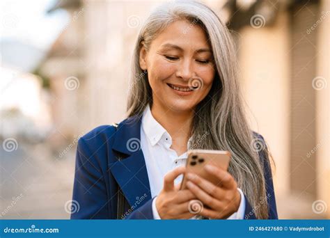 Mature Asian Woman With Grey Hair Smiling And Using Mobile Phone Stock