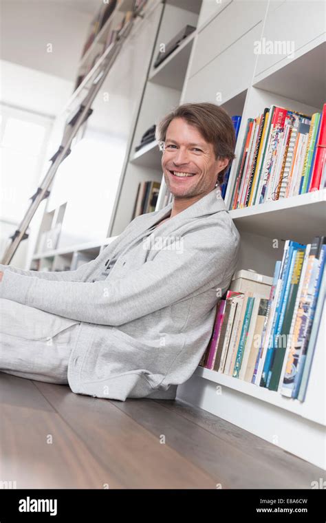 Portrait Of Mature Man Sitting In Front Of Bookshelf Smiling Stock Photo Alamy