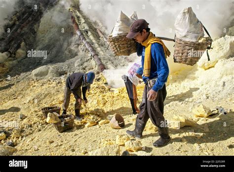 Sulfur Miner Carrying Two Heavy Baskets From The Ijen Volcano Crater