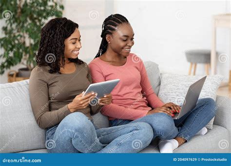 Two African Girlfriends Spending Time At Home Using Gadgets Stock