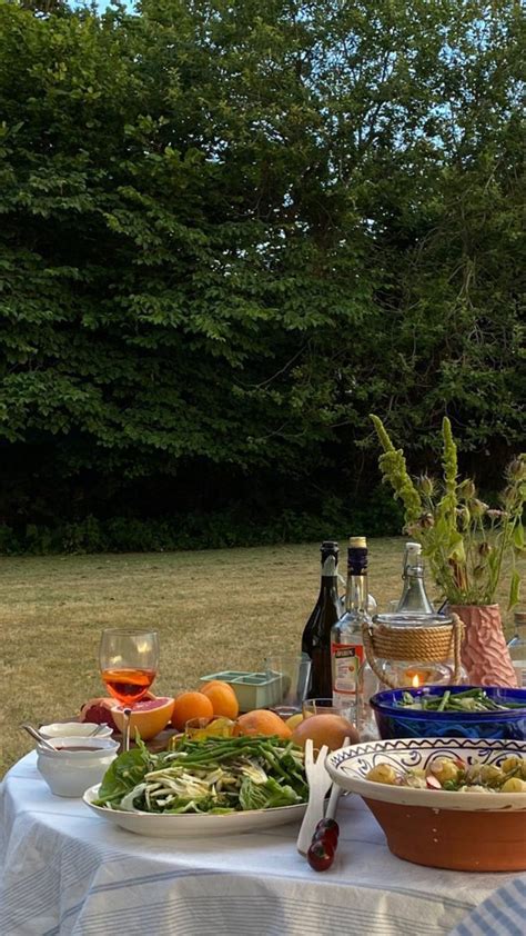 A Table With Food And Drinks On It In The Middle Of A Field Next To Trees