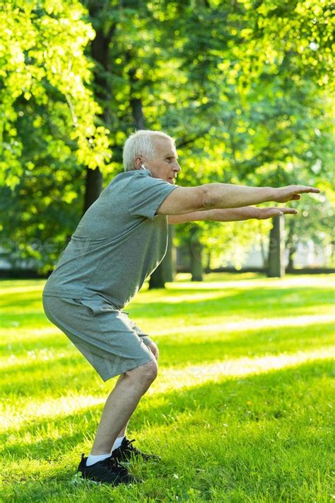 Elderly Man Exercising In Green City Park During His Fitness Workout