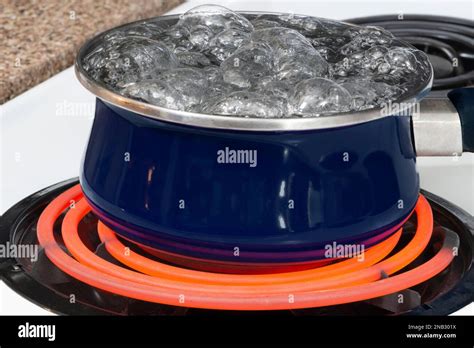 Horizontal Shot Of A Blue Pot On A Stove Top On A Red Hot Burner Holding Boiling Water Stock