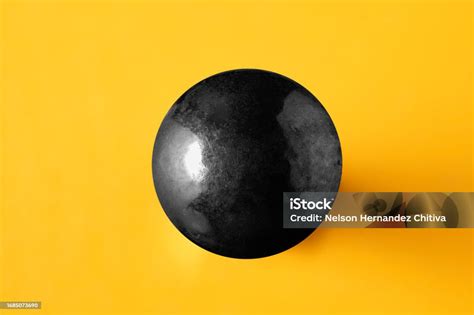 Black Metallic Sphere On Yellow Background Stock Photo Download Image