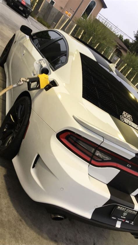 A White Sports Car Is Being Refueled By A Gas Pump At A Gas Station