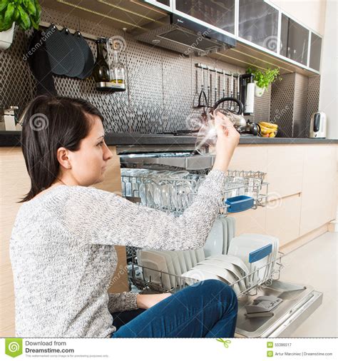 Mujer Que Usa Un Lavaplatos En Una Cocina Moderna Imagen De Archivo