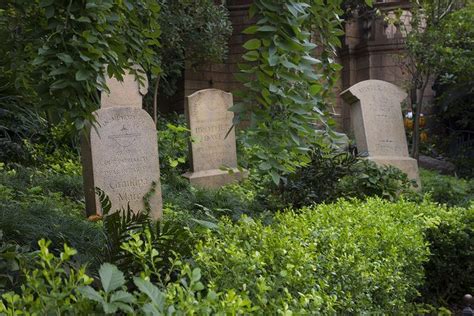 Some Headstones Are In The Bushes Near Trees And Plants On Either Side