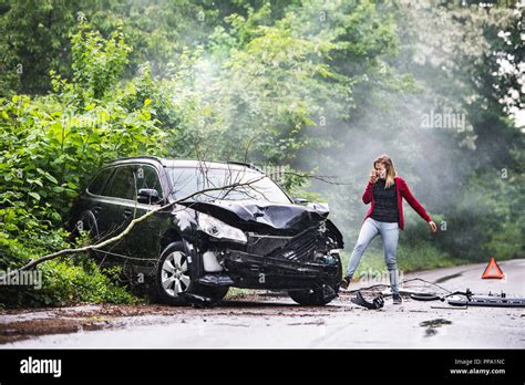 An Angry Young Woman With Smartphone By The Damaged Car After A Car