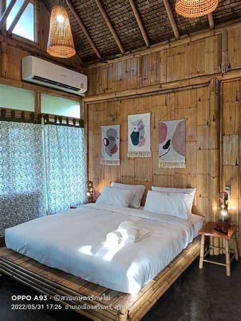 A Bed With White Sheets And Pillows In A Bamboo House Style Bedroom