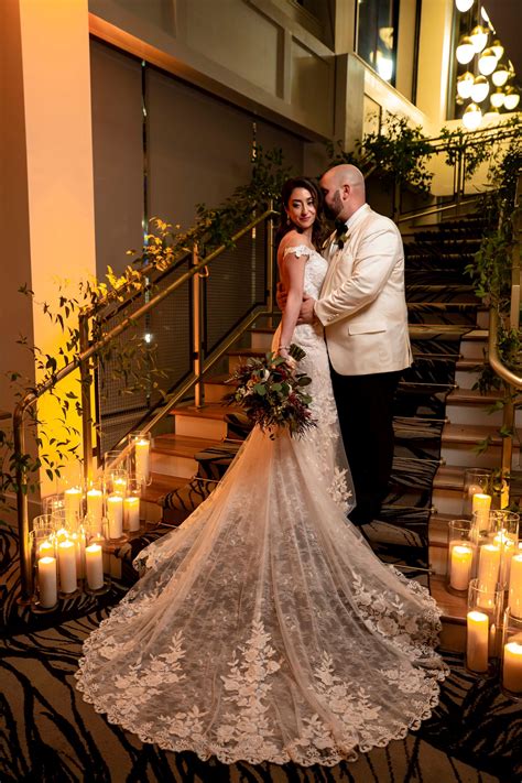 A Bride And Groom Standing In Front Of Candles On The Stairs At Their