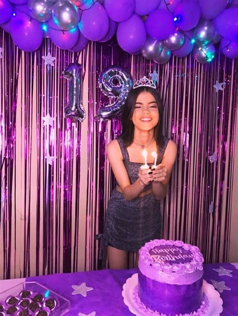 A Woman Standing In Front Of A Purple Cake With Candles On It And