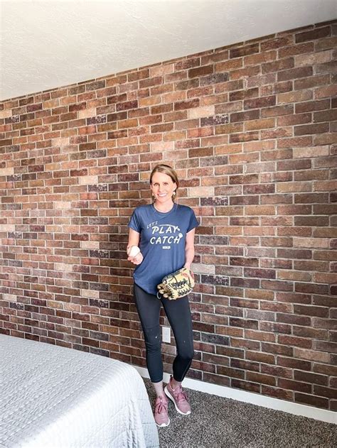 A Woman Standing In Front Of A Brick Wall Holding A Baseball Glove And Mitt