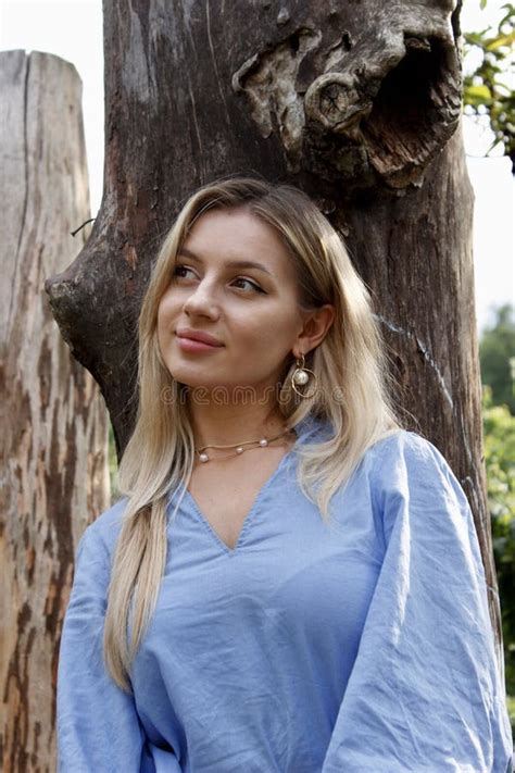 Portrait Of A Pretty Blonde In A Blue Dress Between Big Dry Tree Trunks Stock Photo Image Of