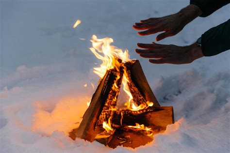 Unrecognizable Male Warms Hands On Fire In Forest During Cold Winter