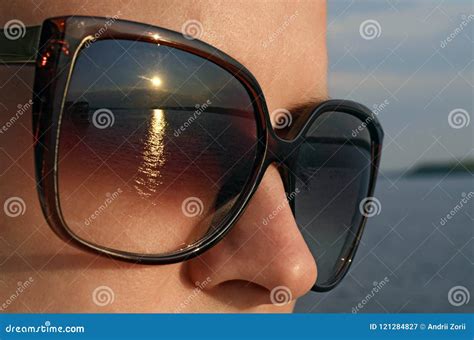 Young Woman In Sunglasses Looks At The Sun On The Beach Stock Image