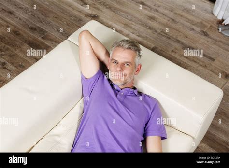 Germany Berlin Mature Man Lying On Sofa Smiling Portrait Stock
