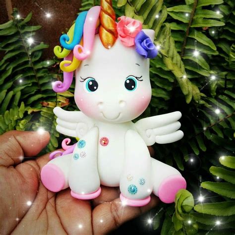 A Hand Holding A Small White Toy With Rainbow Hair And Wings On It S Head