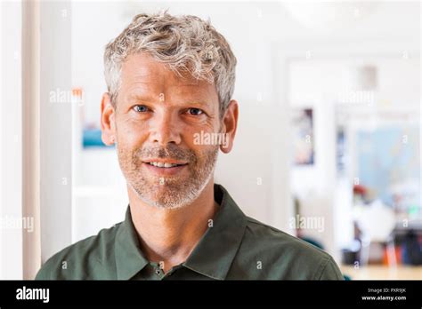 Portrait Of Smiling Mature Man With Grey Hair And Stubble At Home Stock