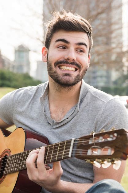 Hombre Joven Sonriente Hermoso Que Toca La Guitarra En Al Aire Libre