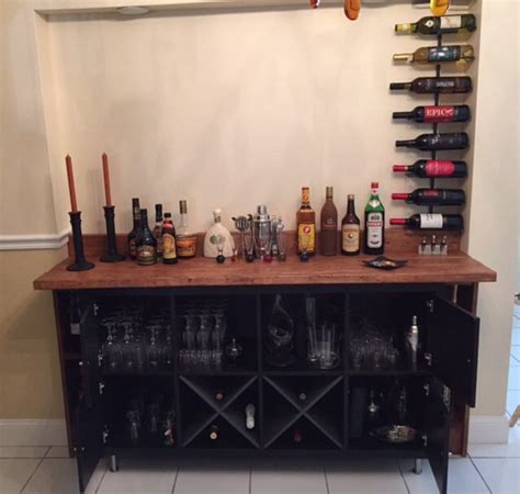 A Wooden Table Topped With Lots Of Bottles And Glasses Next To A Wall