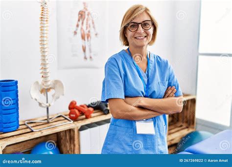 Middle Age Blonde Woman Wearing Physio Therapy Uniform Standing With Arms Crossed Gesture At