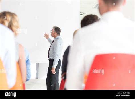 Mature Businessman Explaining Strategy On Projector Screen To