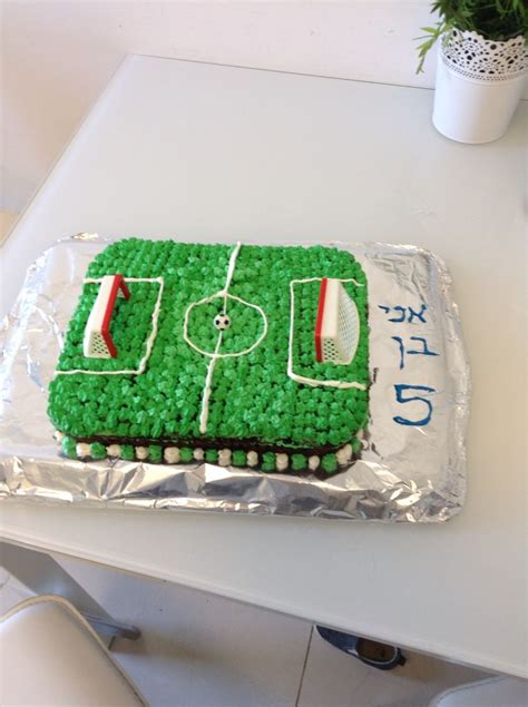 A Cake Shaped Like A Soccer Field On Top Of A White Table Next To A