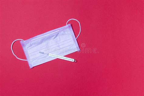 Pink Medicine Facemask And Mercury Thermometer On Red Background With