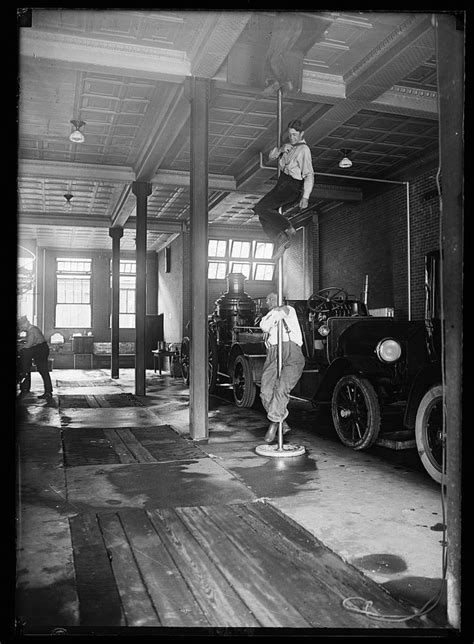 An Old Black And White Photo Of Men Working On Cars In A Garage With