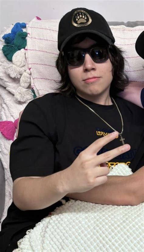 A Man And Woman Laying On Top Of A Bed Wearing Black Hats Sunglasses