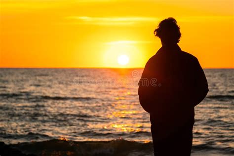 Silueta Oscura De Un Hombre Parado Junto Al Mar Al Atardecer Dorado