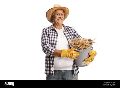 Happy Mature Farmer Holding A Bucket Full Of Hay Isolated On White